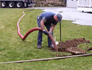 Septic pumping technician servicing a residential septic tank with a vacuum hose in Vancouver, WA