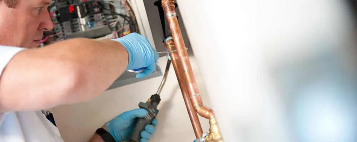 Water heater repair technician testing copper pipe connections and controls in Vancouver, WA